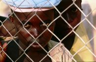 Tutsi boy behind cyclone fence.