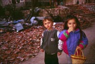 Two children standing in rubble.